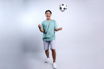 Full Length Of Happy Young Asian Man Clenching Fist Showing Victory With Flies Soccerball, Winning...