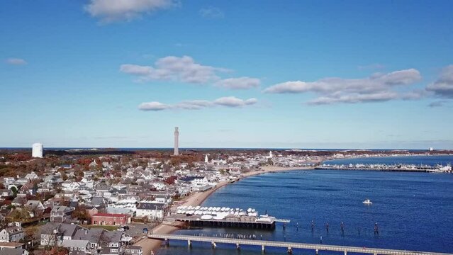 Aerial footage of Provincetown, Massachusetts, featuring the iconic Pilgrim Monument towering over a picturesque coastal town with charming houses and a serene waterfront.