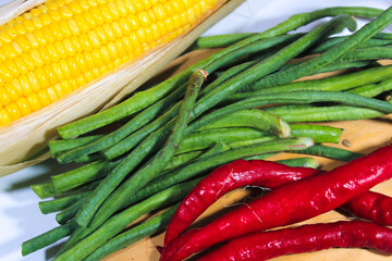long red chilies and sweet corn on a plastic white plate photographed closeup