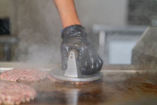 Chef cooking smash burgers on the restaurant griddle