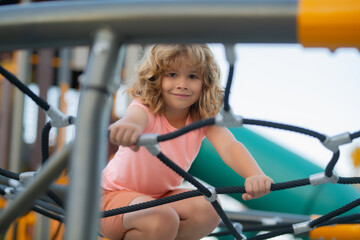 Portrait of child doing rock climbing with background playground.