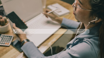 A business woman in a blue shirt uses her hand to hold a pen and her left hand to hold a smartphone...