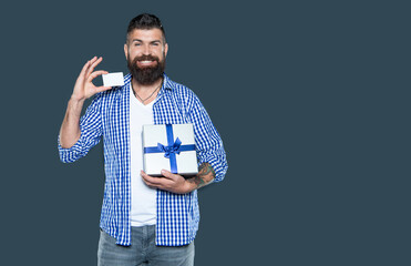 cheerful mature bearded man with present box and card