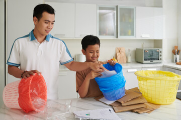 Father and son sorting waste at home, Earth day concept