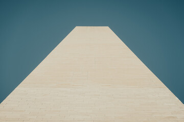 Fototapeta premium pillar made of sandstone in front of blue sky in warm colors - looking up forming a trapezoid shape