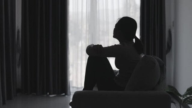 Silhouette of a woman who is stressed and suffering from depression alone. Anxiety young woman Despair and stress. Lonely and unhappy female are social victims. loneliness youth in home.