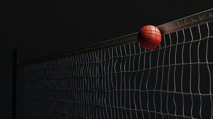 A dramatic close-up of a volleyball caught in a net. The ball is orange and the net is black and white.