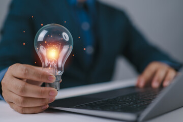Innovation concept. Businessman holding brain light bulb on virtual screen icon for creative idea.