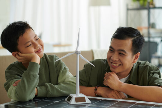 Smiling father and son looking at model of wind turbine