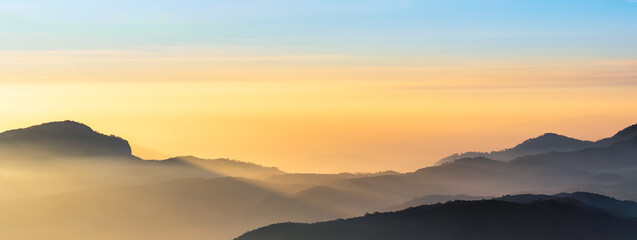 Mountain range panorama in sunrise sky, mountain ridge in sunlight.