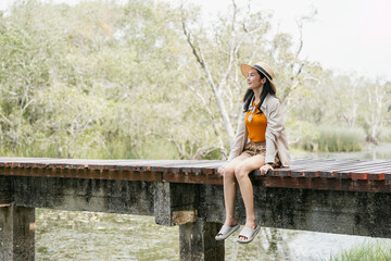 Young asian woman traveling alone in the forest. Happy weekend on vacation time. Attractive female traveler walking in nature spend time enjoy with holiday