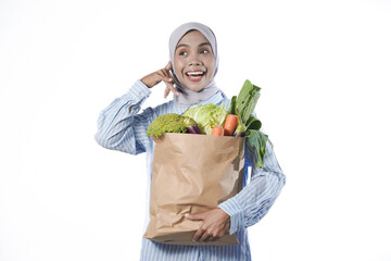 Young woman wear casual clothes hold brown paper bag with vegetable products isolated on white background studio portrait