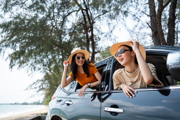 Two asian female friend travel by car on a bright day to the sea sand beach with beautiful blue sky sunlight. They was happy along the way trip. safety driving car vacation on weekend