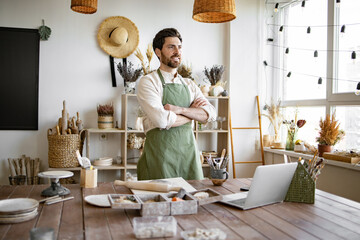 Portrait of mature bearded male potter, standing in front of table with tools for sculpture....