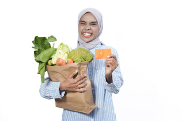 Young woman wear casual clothes hold brown paper bag with vegetable products mock up of credit bank card isolated on white background studio portrait