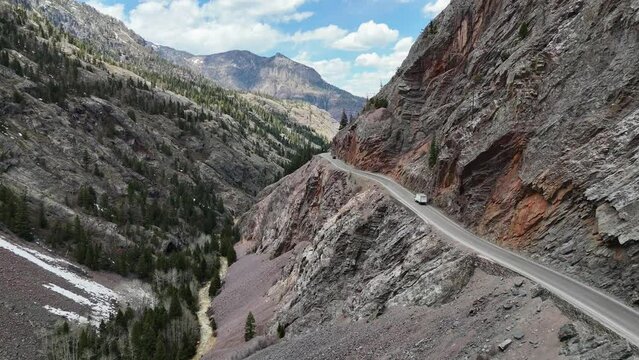 Drone view of Storage Truck driving down a dangerous narrow road on the edge of a mountain, red mountain pass, highway 550, million dollar highway in Ouray Colorado