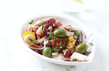Salad with tuna, green olives and cherry tomatoes. Bright wooden background. Close up. Copy space.