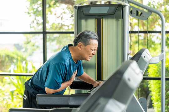 Senior sporty person in sports uniform running on treadmill. Old man  he felt a pain in his chest held his hand and squeezed it. Mature Heart attack that needed treatment.