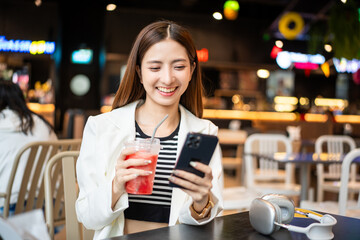 Young asian smiling woman with soft drink sitting in the coffee shop cafe. Business woman laughing talking with friend inside restaurant. People lifestyle concept.