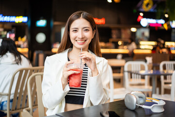 Young asian smiling woman with soft drink sitting in the coffee shop cafe. Business woman laughing talking with friend inside restaurant. People lifestyle concept.