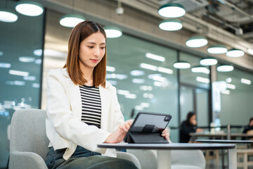 Young asian businesswoman with tablet working in the office. Start up freelancer people posing while using digital tablet working in the modern office. Lifestyle business female.