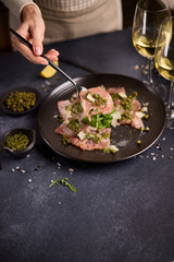tuna carpaccio - slices of fresh raw tuna fillet on black ceramic plate