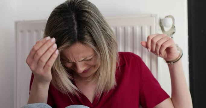 Woman in handcuffs sits on floor and cries