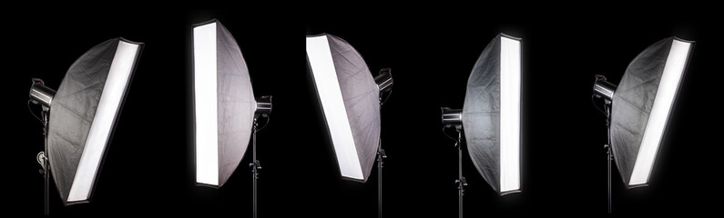 Photography studio flash on a lighting stand isolated on black background.