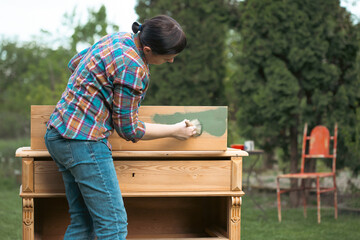 Woman painting a wooden furniture outdoors, an eco-friendly re-use business.
