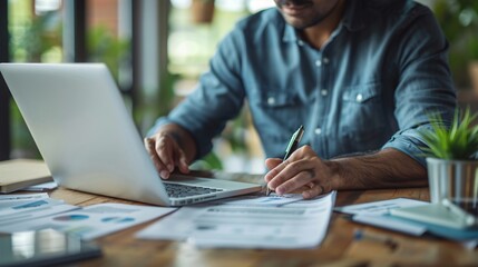 Man sits table laptop pen
