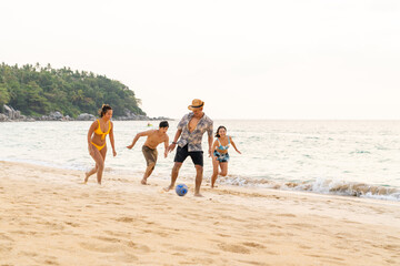 Group of Happy Asian man and woman enjoy and fun outdoor lifestyle travel at the sea on summer beach holiday vacation. People friends playing ball together on tropical island beach at sunset.