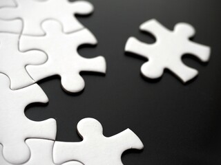 Fototapeta premium Unfinished white jigsaw puzzle on a black background