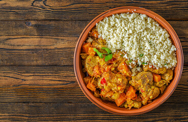 A rustic tabletop feast: a steaming lamb and pumpkin tagine sits alongside fluffy couscous and a...
