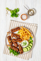 minced beef skewers with potato fries on plate