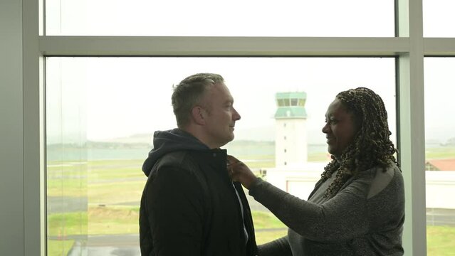 Black Women and Caucasian Male at Airport, looking at each other, she boops his nose.