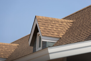 Roof shingles with garret house on top of the house. dark brown asphalt tiles on the roof...