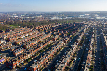 Aerial photo of the village of Beeston in Leeds West Yorkshire showing a typical British park along side rows of terrace houses, roads and streets, taken in the winter time on a wet cold day.