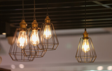 A group of four lighted lamps hanging from the ceiling