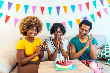 Friends celebrating birthday with cake at home