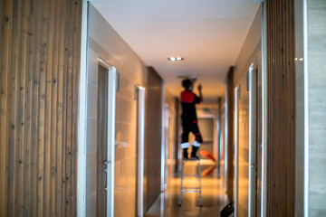 Blurry picture of Technician is replacing or repair a smoke detector in an office building or...