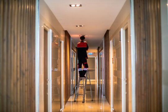 Technician is replacing or repair a smoke detector in an office building or condominium.  Technician is checking a fire alarm system at smoke detector.