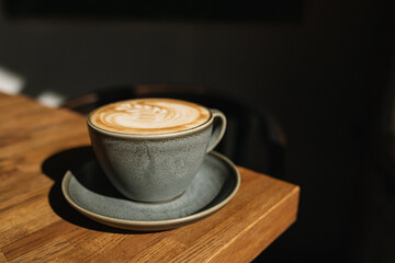 Cup of coffee on a wooden table in the sunlight.