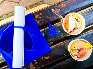 Graduation oath paper with tassel and two party cakes in paper cups on graduation day event in Tbilisi, Georgia