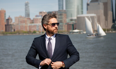 Confident rich business man executive standing in New York City. Business American success. American business dream. American businessmen in suits near Manhattan. Successful business in USA.