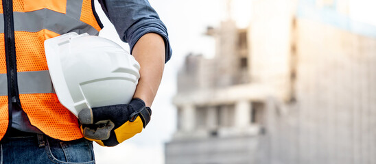 Safety workwear concept. Male hand holding white safety helmet or hard hat. Construction worker man...