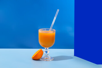 A glass of refreshing orange juice with a blue tint is placed on a table