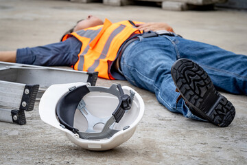 Accident and injury on a construction site. Safety first concept. Male worker lying down unconscious on the floor with safety helmet after falling from ladder. Fainting from exhaustion or heat stroke