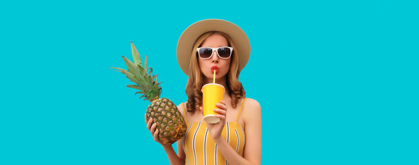 Summer portrait of stylish young woman drinking fresh juice with pineapple fruit on blue background