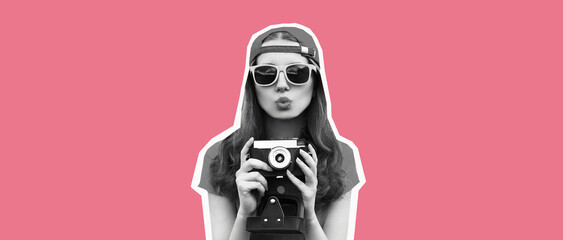 Stylish happy young woman photographer taking picture on camera blowing a kiss on pink background