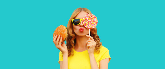 Portrait of happy cheerful young woman with burger fast food and sweet lollipop